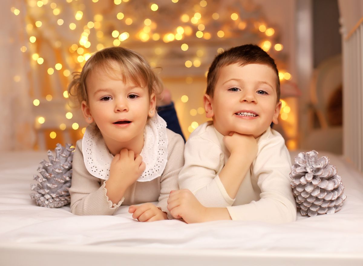 Dva malí sourozenci na vánoční fotografii se světelným řetězem