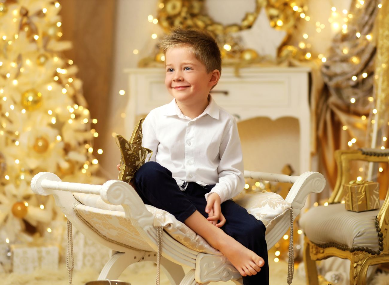 Vánoční fotka malého kluka s vánočními rekvizitami a dárky v ateliéru