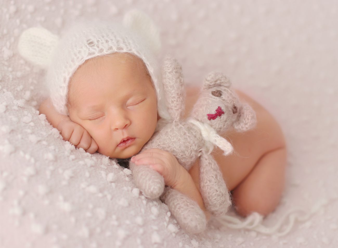 Fotografie novorozeného miminka s čepičkou a medvídkem