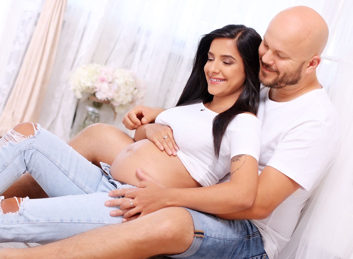 Partner na ateliérové těhotenské fotografii objímá těhotnou maminku