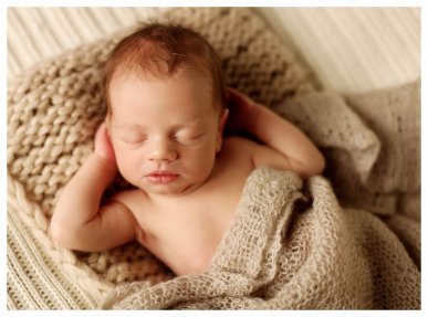 Spící novorozeně s rukama pod hlavou na ateliérové fotografii