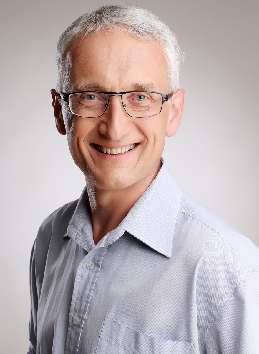 Fotografie na CV muže ve středních letech ve světle modré rozhalence s výrazným úsměvem a brýlemi na šedém pozadí v ateliéru. | © Fotoprome.cz