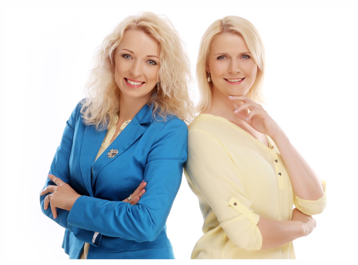 Profesionální business fotografie dvou kolegyň na bílém pozadí v ateliéru Fotoprome.cz v Praze. Usmívající se dámy jsou opřené zády a mají na sobě modrý a žlutý elegantní kancelářský kostým. | © Fotoprome.cz, Praha 7