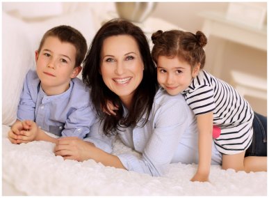 Máma a dvě děti si užívají společné rodinné fotografování na posteli ve fotoateliéru Fotoprome.cz.